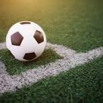 Bola de futebol sobre a marcação de escanteio em gramado sintético
