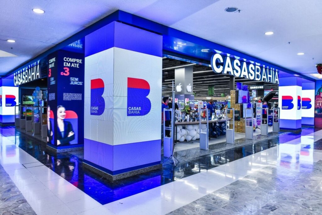 Loja da Casas Bahia em shopping com iluminação azul e exibição de produtos eletrônicos