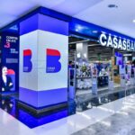 Loja da Casas Bahia em shopping com iluminação azul e exibição de produtos eletrônicos