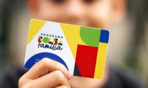 Mão segura cartão do Programa Bolsa Família com design colorido em destaque