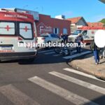 Motocicleta tombada em faixa de pedestres com ambulâncias e pessoas próximas ao local do acidente