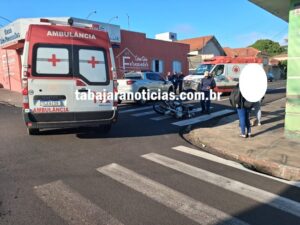 Motocicleta tombada em faixa de pedestres com ambulâncias e pessoas próximas ao local do acidente