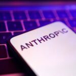 Um smartphone com o nome Anthropic exibido na tela sobre um teclado iluminado em tons de roxo e azul