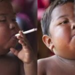 Criança segura cigarro na boca e exala fumaça em close-up