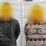 Um homem e uma mulher em frente a parede de medição da Polícia Civil com rostos pixelados