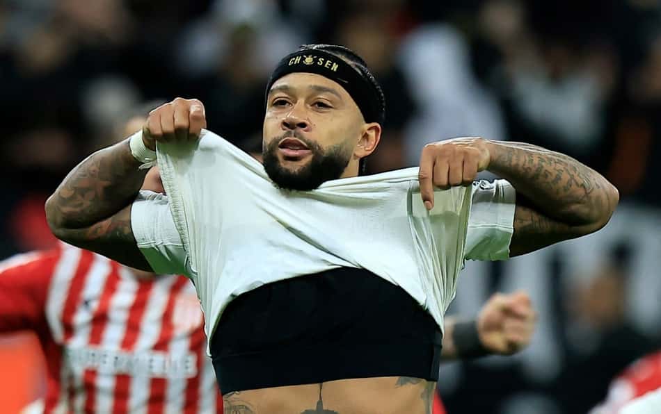Um jogador com tatuagens e faixa na cabeça levanta a camisa em comemoração no campo