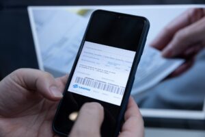 Mãos seguram celular com conta de água digital da Sanepar em tela, ao lado de documento físico