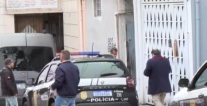Veículo da polícia estacionado em frente a residência com pessoas ao redor