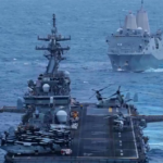 Navios militares navegando em águas abertas com helicópteros no convés