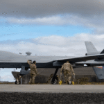 Um drone MQ-9 é preparado por militares em pista de aeroporto sob céu nublado
