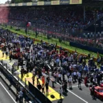 Pista de corrida com multidão em arquibancadas e carros temáticos no grid