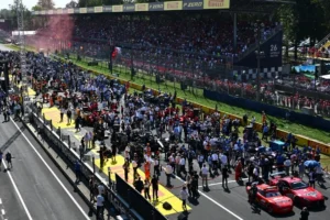 Pista de corrida com multidão em arquibancadas e carros temáticos no grid