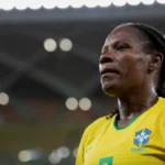 Mulher com camisa amarela da seleção brasileira em campo de futebol iluminado