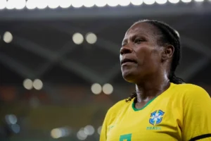 Mulher com camisa amarela da seleção brasileira em campo de futebol iluminado