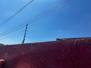 Muro rosa com fios elétricos sob céu azul claro em área urbana