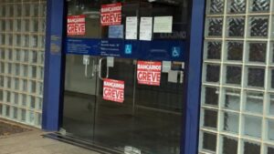 Porta de agência com cartazes vermelhos anunciando greve de bancários