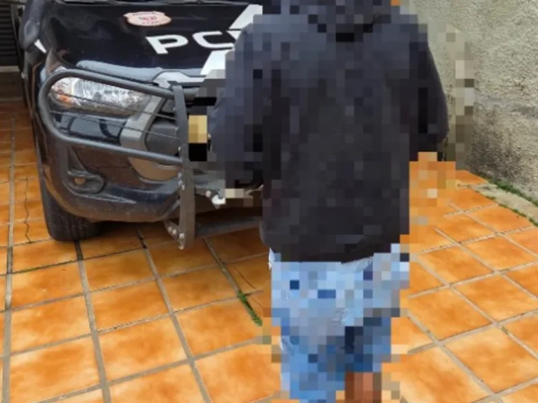 Um homem de costas caminha ao lado de veículo da PC em piso de ladrilho