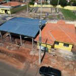 Construção de estrutura com telhado metálico em área urbana próxima a escola e quadra de esportes