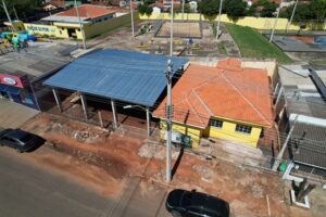 Construção de estrutura com telhado metálico em área urbana próxima a escola e quadra de esportes