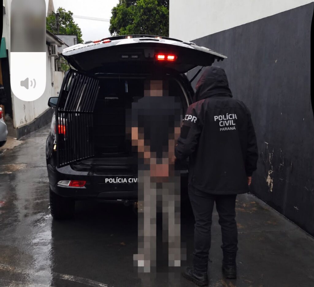 Um adolescente é conduzido para dentro do porta-malas de uma viatura da Polícia Civil em dia chuvoso