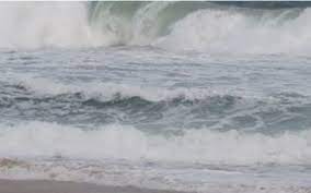 Ondas fortes e espumantes se quebram com intensidade na beira da praia