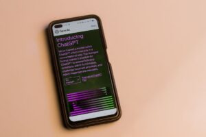 Um smartphone exibe a tela inicial do ChatGPT da OpenAI com texto e botões de acesso