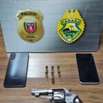 Revólver, munições e dois celulares sobre mesa em frente a placa de operação conjunta com emblemas de Polícia Civil e Polícia Militar do Paraná