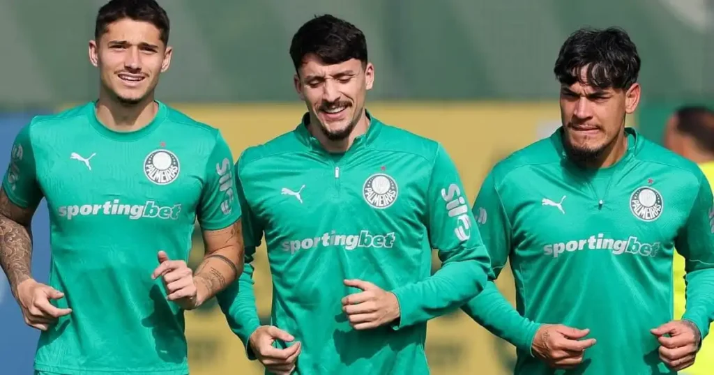 Três homens em uniformes verdes do Palmeiras durante treino ao ar livre
