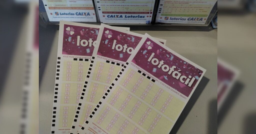 Três volantes da Lotofácil sobre uma superfície, com caixas de apostas ao fundo