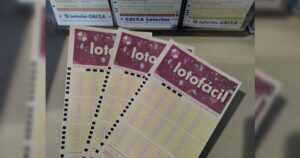 Três volantes da Lotofácil sobre uma superfície, com caixas de apostas ao fundo