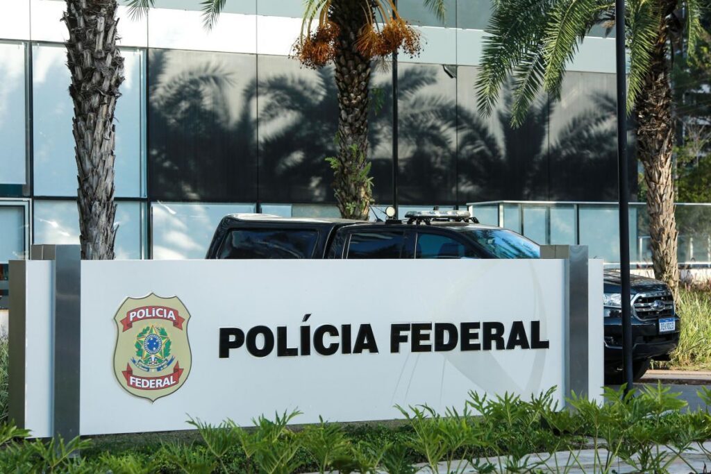 Veículo estacionado em frente a sede da Polícia Federal, com placa e brasão visíveis