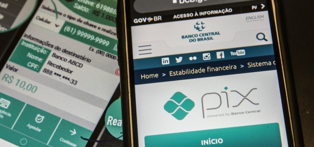 Dois celulares exibem telas com o sistema Pix e informações de transferência financeira