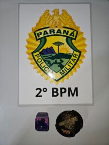 Objetos apreendidos em frente ao brasão da Polícia Militar do Paraná, com inscrição 2º BPM