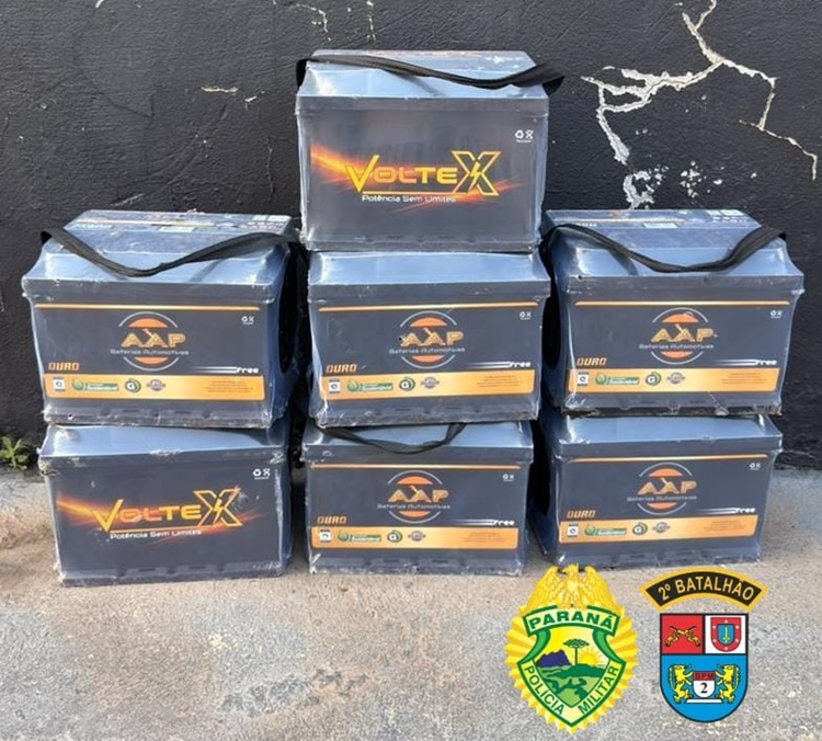 Sete baterias empilhadas em frente a parede, com logotipos de marcas e emblemas da Polícia Militar do Paraná