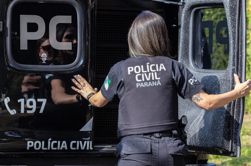 Mulher com uniforme da Polícia Civil do Paraná abre porta de veículo com inscrições "PC" e "197