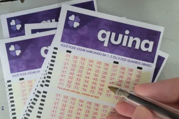 Mão segura caneta sobre volante da Quina com números marcados em quadros numerados