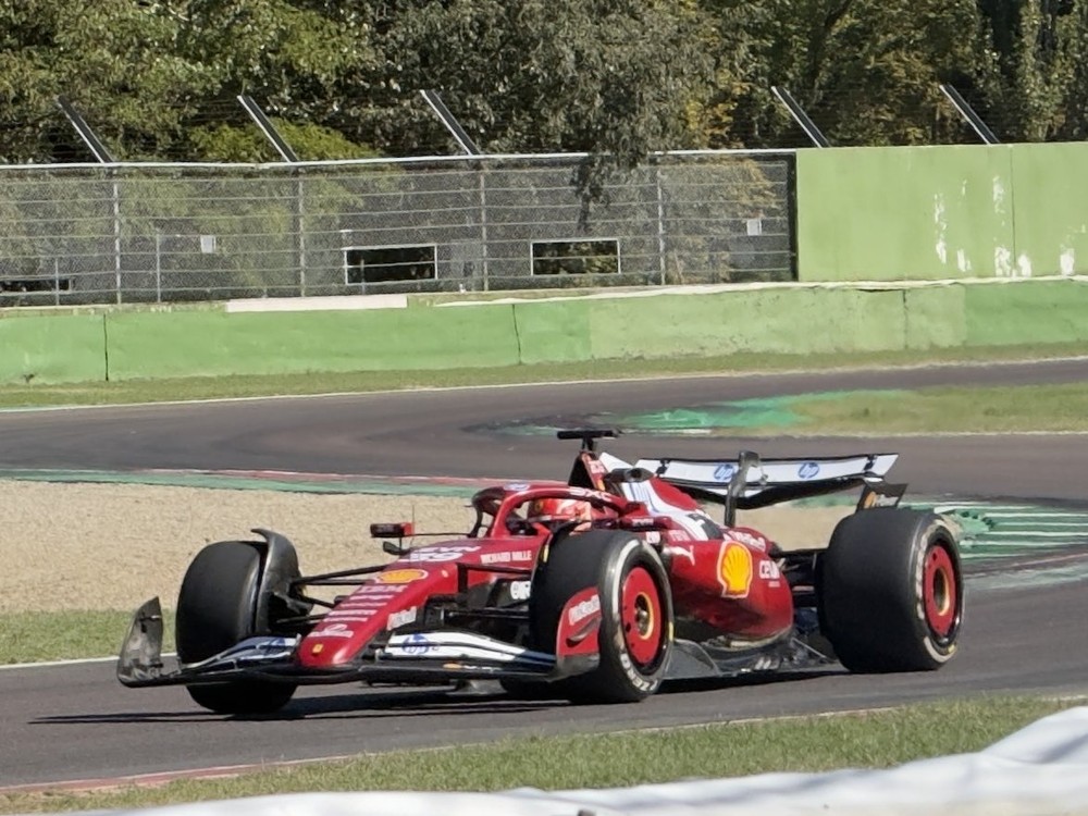 Um carro de Fórmula 1 vermelho com patrocínios visíveis em movimento em uma pista de corrida