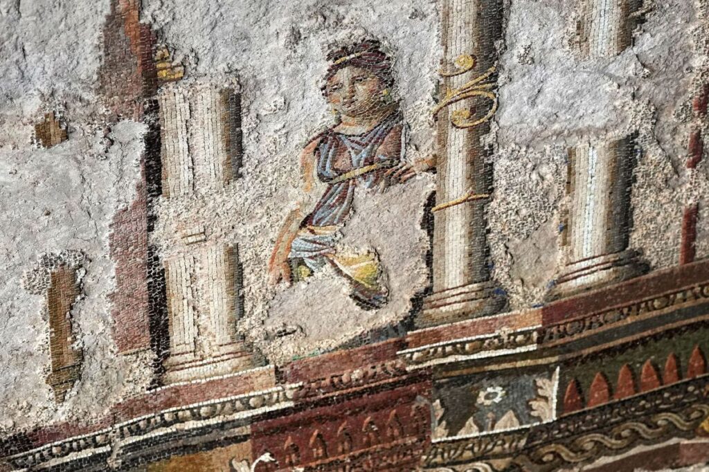 Detalhe de mosaico romano em escavação com figura feminina entre colunas e ornamentos coloridos