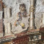 Detalhe de mosaico romano em escavação com figura feminina entre colunas e ornamentos coloridos