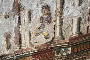 Detalhe de mosaico romano em escavação com figura feminina entre colunas e ornamentos coloridos