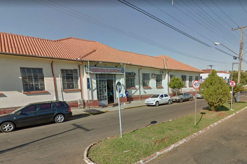 Fachada de um prédio com placa de Misericórdia de Jacarezinho, veículos estacionados na rua ao lado