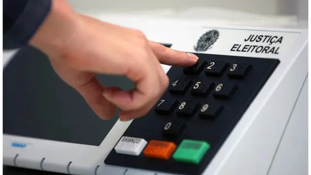 Mão apertando tecla em urna eletrônica da Justiça Eleitoral