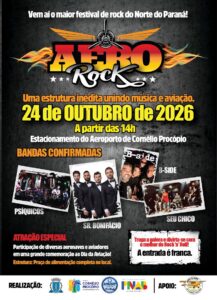 Um grupo de pessoas posa em frente a um palco com instrumentos musicais em um evento de rock ao ar livre