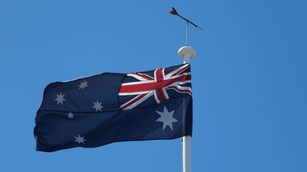 Bandeira da Austrália hasteada em mastro com céu azul ao fundo