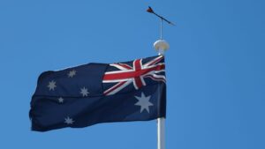 Bandeira da Austrália hasteada em mastro com céu azul ao fundo