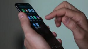 Um homem de terno segura um celular com aplicativos visíveis na tela