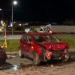 Um carro vermelho com a frente destruída após colisão em via noturna com outro veículo
