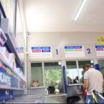 Pessoas fazem apostas em frente a caixas de loteria com placas de jogos acumulados