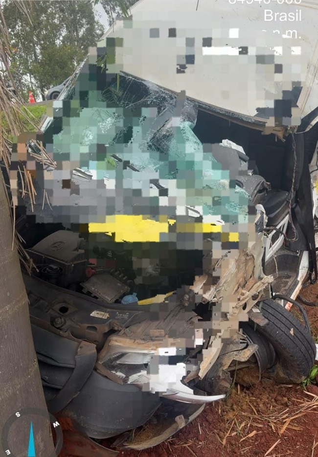 Um carro com a frente destruída após colisão lateral em via rural