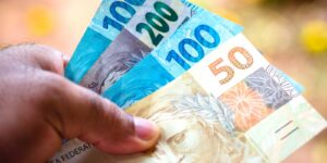 Uma mão segura notas de real de diferentes valores em foco próximo